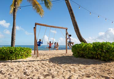 Three kids the beach swinging on a swingset at Royal Cancun Resort in Mexico.