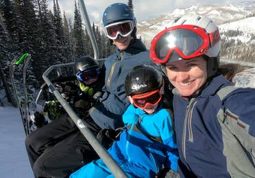 Author, Jessica Averett, and her family sit on the ski lift in winter apparel and ski gear.