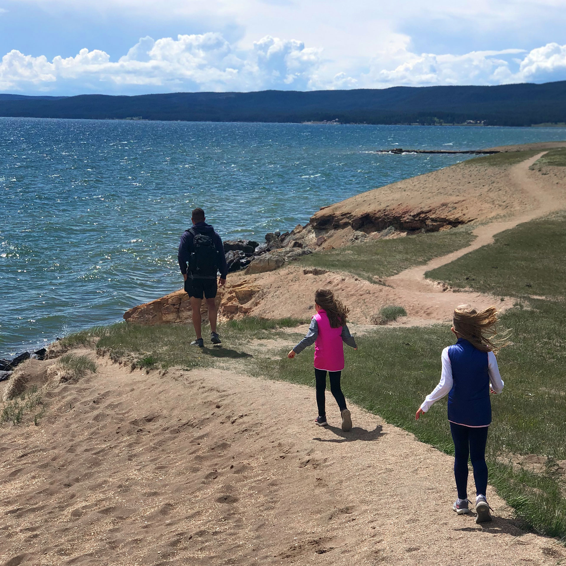 Author, Chris Johnstons' husband, Josh (far-left), walks towards the lake at Yellowstone National Park with their daughters, Kyndall (front-right), and Kyler (middle.