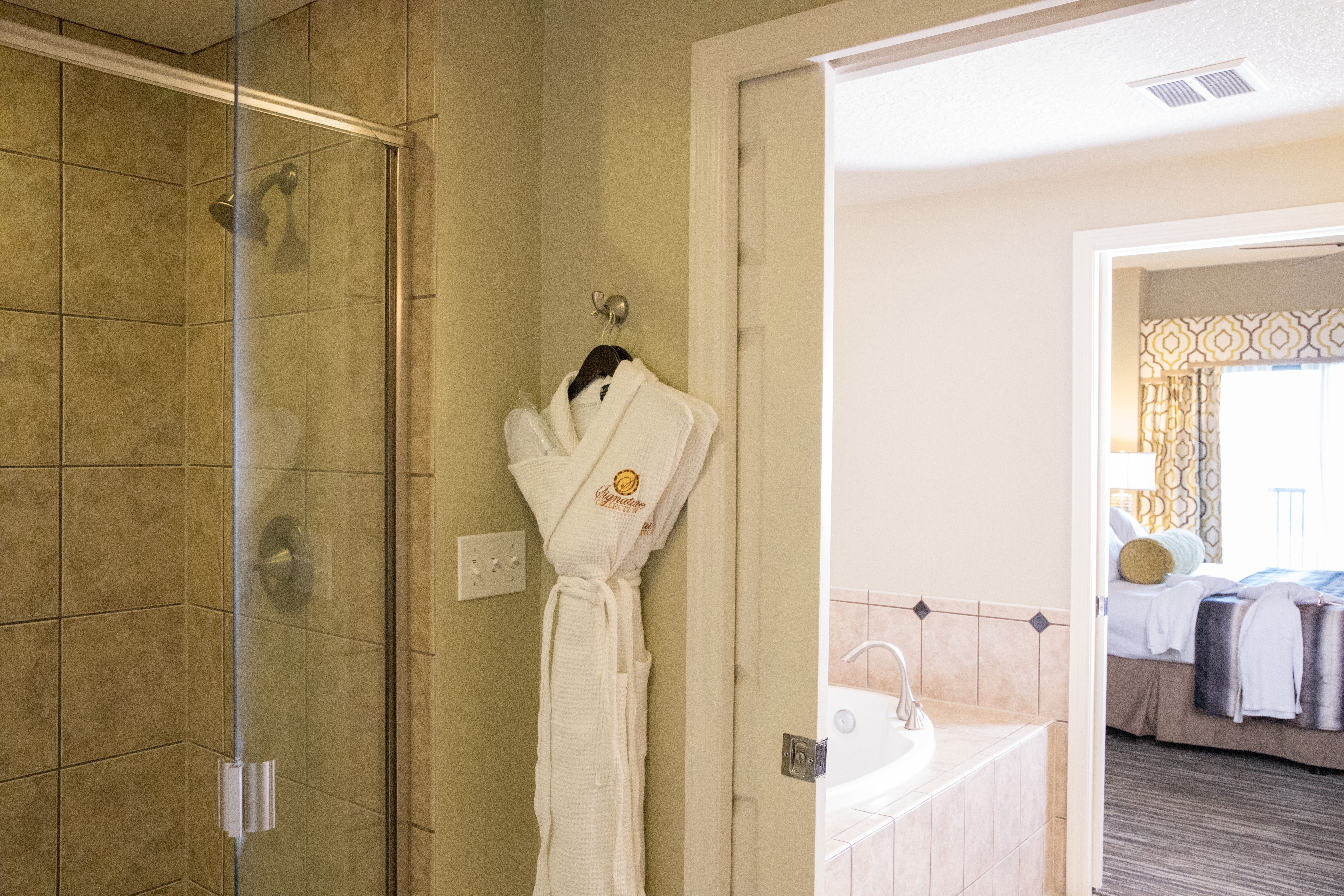 Bathroom with walk-in shower, soaking tub, and complimentary robe in a four bedroom Signature villa in River Island at Orange Lake Resort near Orlando, Florida