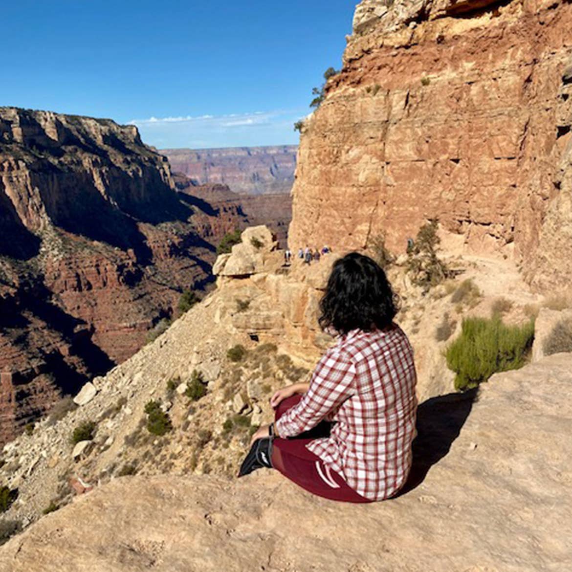 Noemi sits near the edge of the Grand Canyon overlooking the vibrant orange ridges.