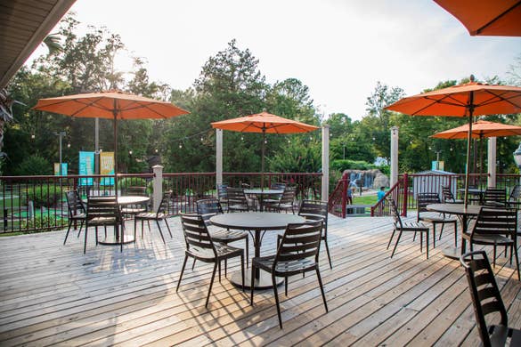 The patio of our Activities Outpost with patio tables and umbrellas at our Villages Resort located in Flint, Texas.