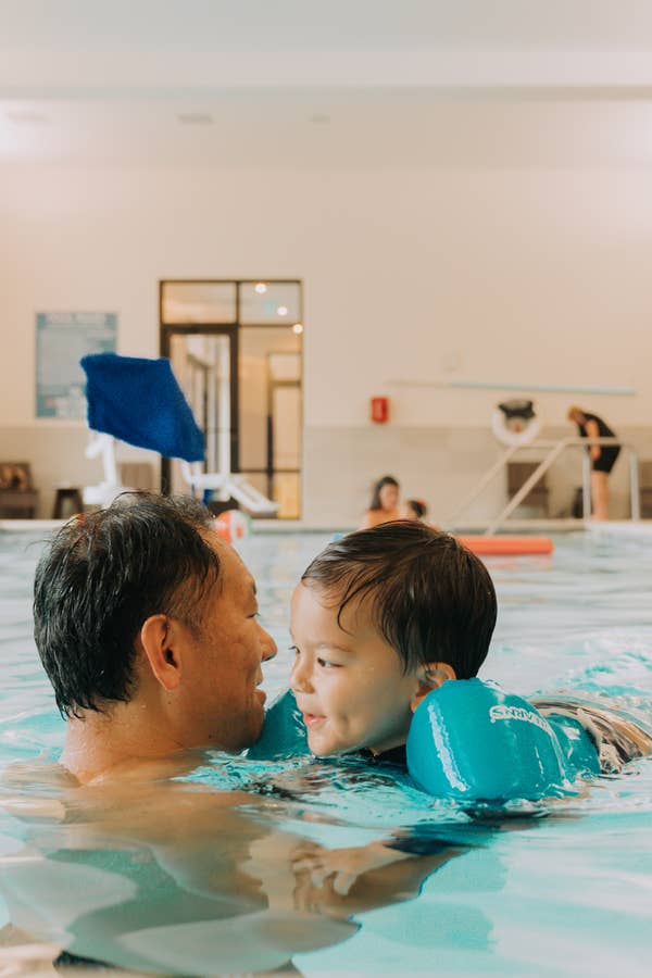 Adult and child in indoor swimming pool at Williamsburg Resort in Virginia.