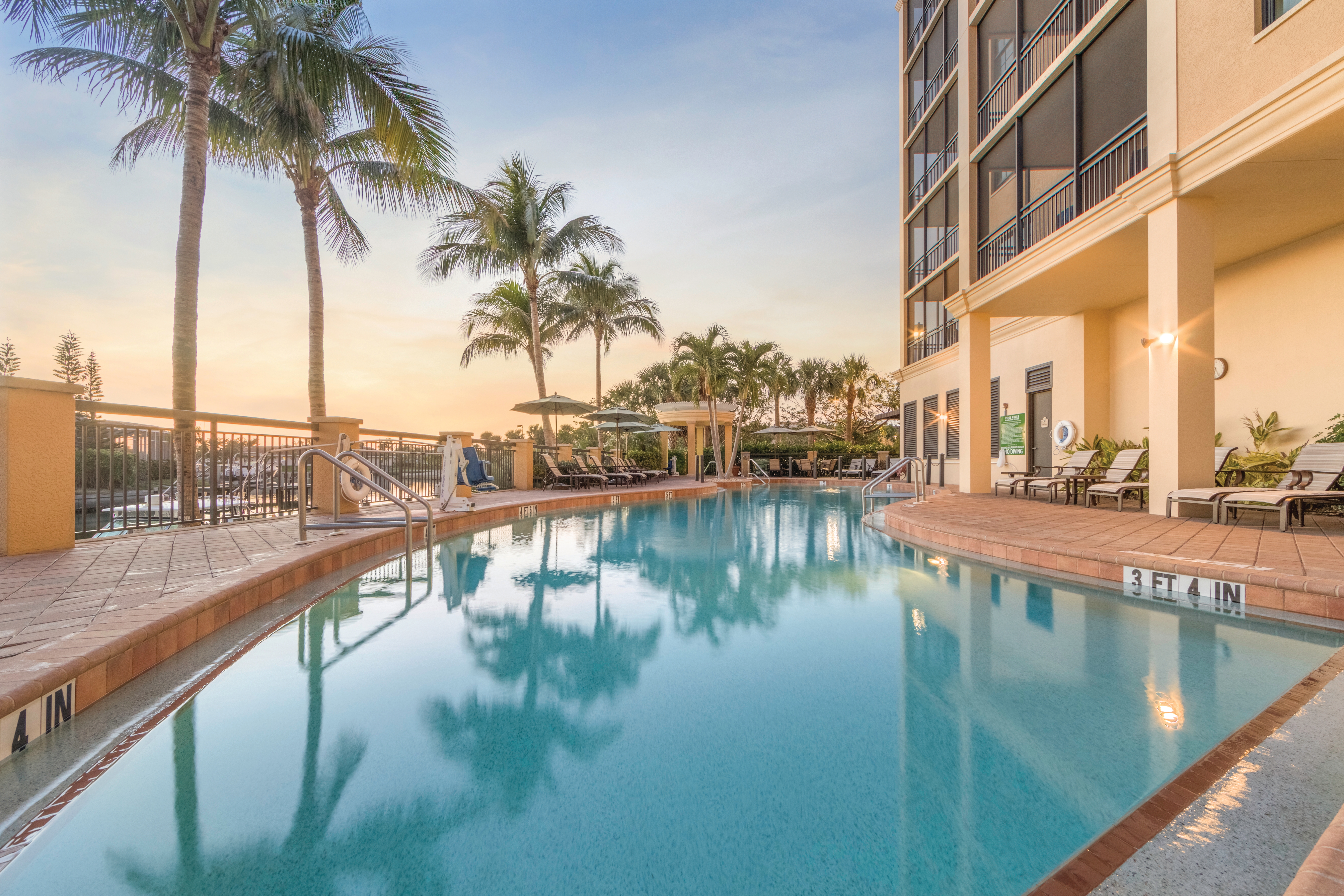Outdoor pool surrounded by palm trees at Sunset Cove Resort in Marco Island, Florida.