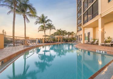 Outdoor pool surrounded by palm trees at Sunset Cove Resort in Marco Island, Florida.