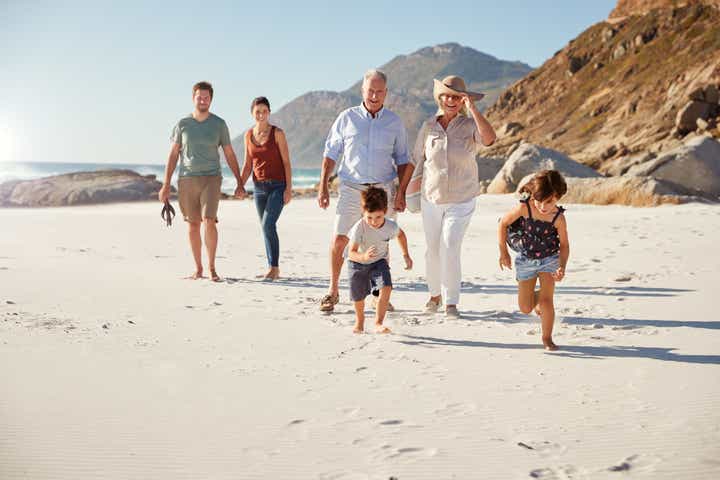 Family walking in the sand at a beach surrounded by large rocking hills
