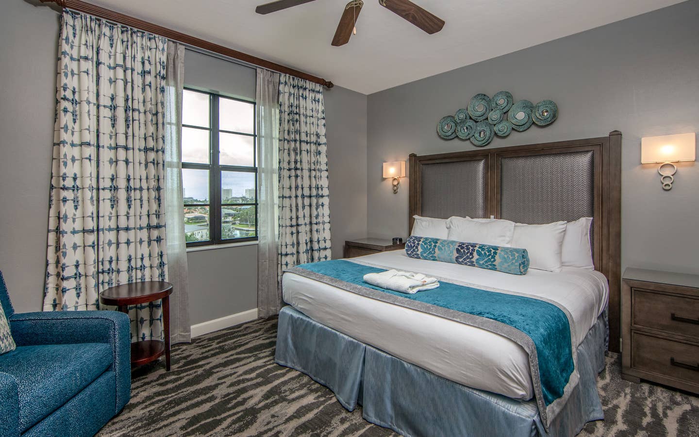 Bedroom with king bed, large window, seating area, and ceiling fan in a three-bedroom villa at Sunset Cove Resort in Marco Island, Florida