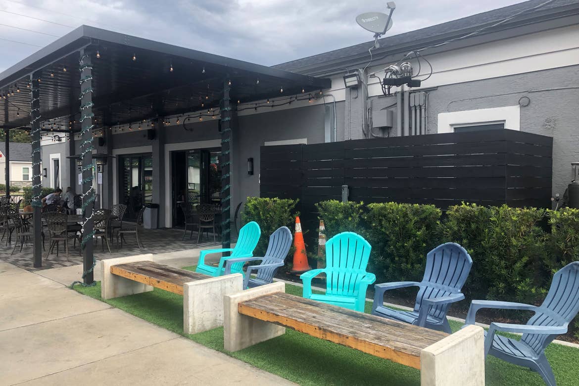 A covered patio exterior and multi-colored Adirondack chairs outside of 'Hourglass Brewing.'