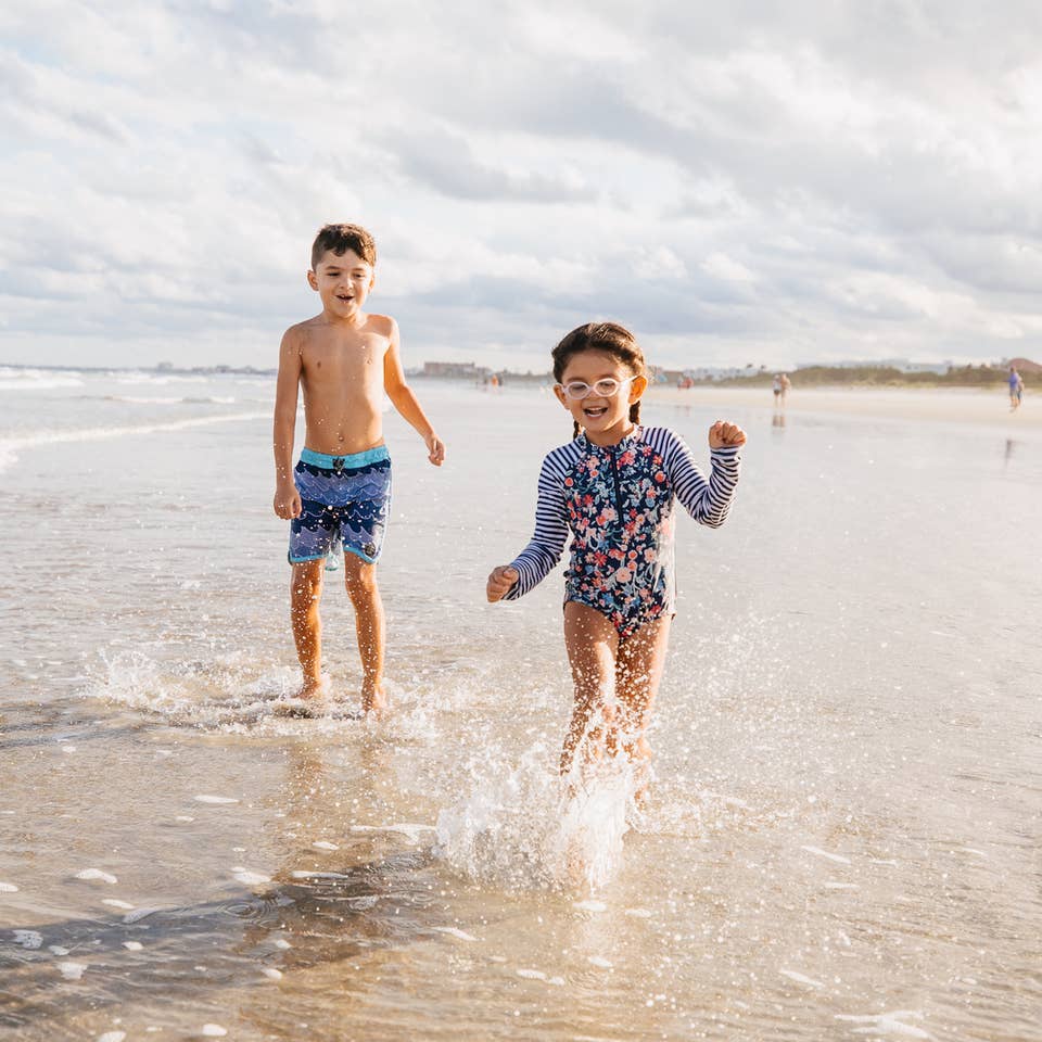 Two children running on beach near Cape Canaveral Beach Resort in Florida.