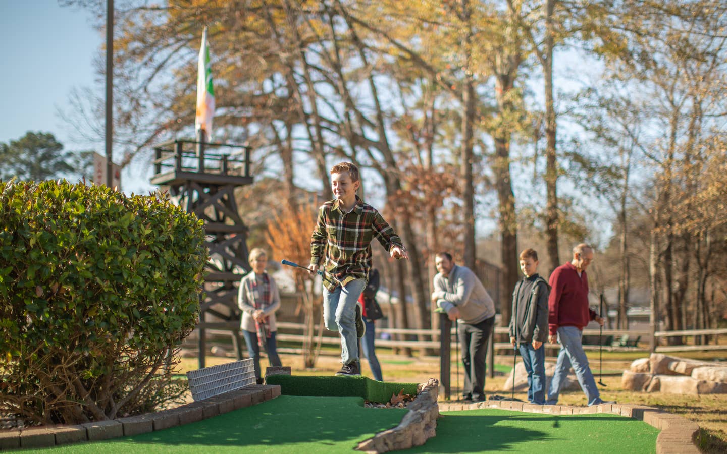 Family playing mini golf with fall foliage in the background at Villages Resort in Flint, Texas.