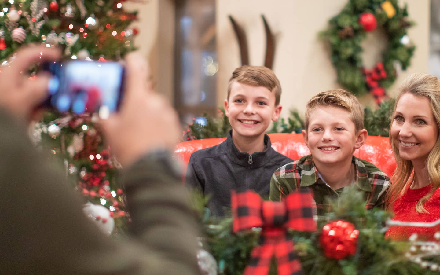 Author, Amanda Nall (left), pose on Santa's sleigh with her sons for a photograph surrounded by holiday decor.