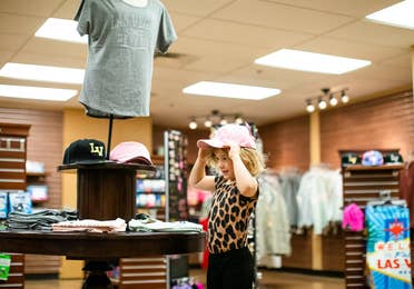 Young child trying on pink Las Vegas hat in the Marketplace at Desert Club Resort in Las Vegas, Nevada
