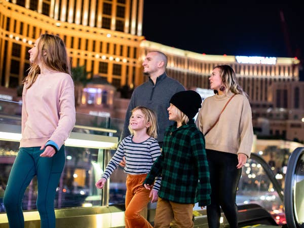 Family of five walking through Las Vegas at night near Desert Club Resort in Nevada.