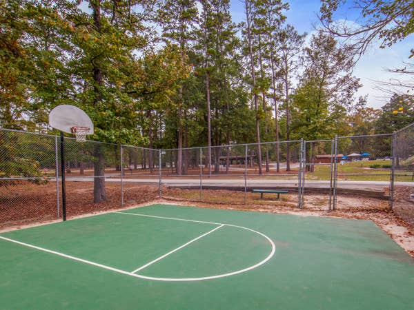Outdoor basketball court with one hoop at Holly Lake Resort in Texas.