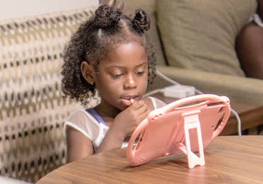 Author, Kimberly Gelin's daughter (left), sits at her dining table in our Villa at Orange Lake Resort in Florida with her iPad for virtual learning.