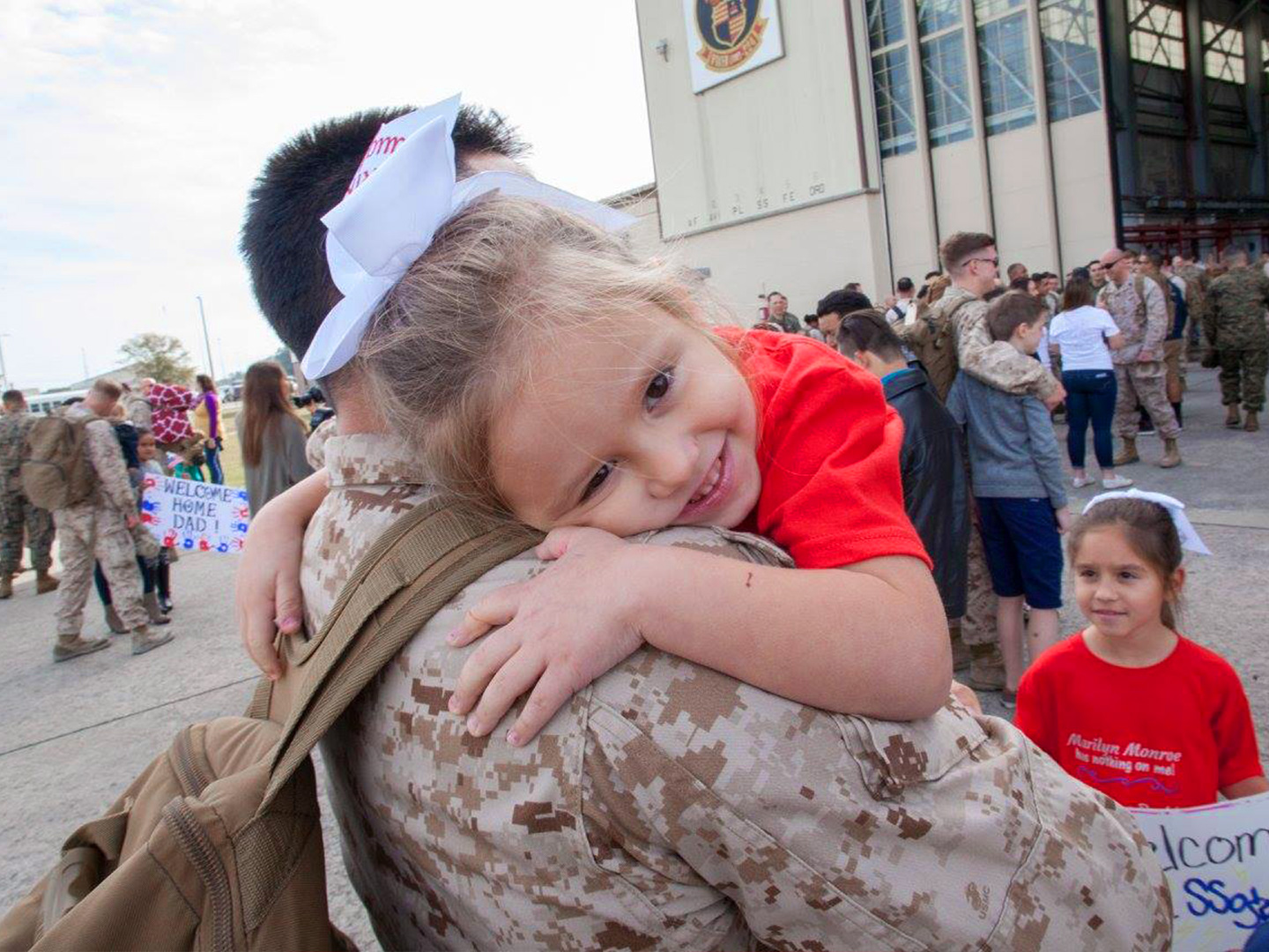 Sara Perezes youngest daughter (right) is held by her dad in his uniform outside of an air hangar.
