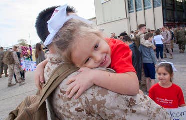 Sara Perezes youngest daughter (right) is held by her dad in his uniform outside of an air hangar.