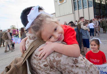 Sara Perezes youngest daughter (right) is held by her dad in his uniform outside of an air hangar.