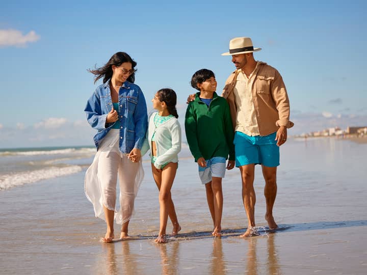 A family of five walking together beside the ocean