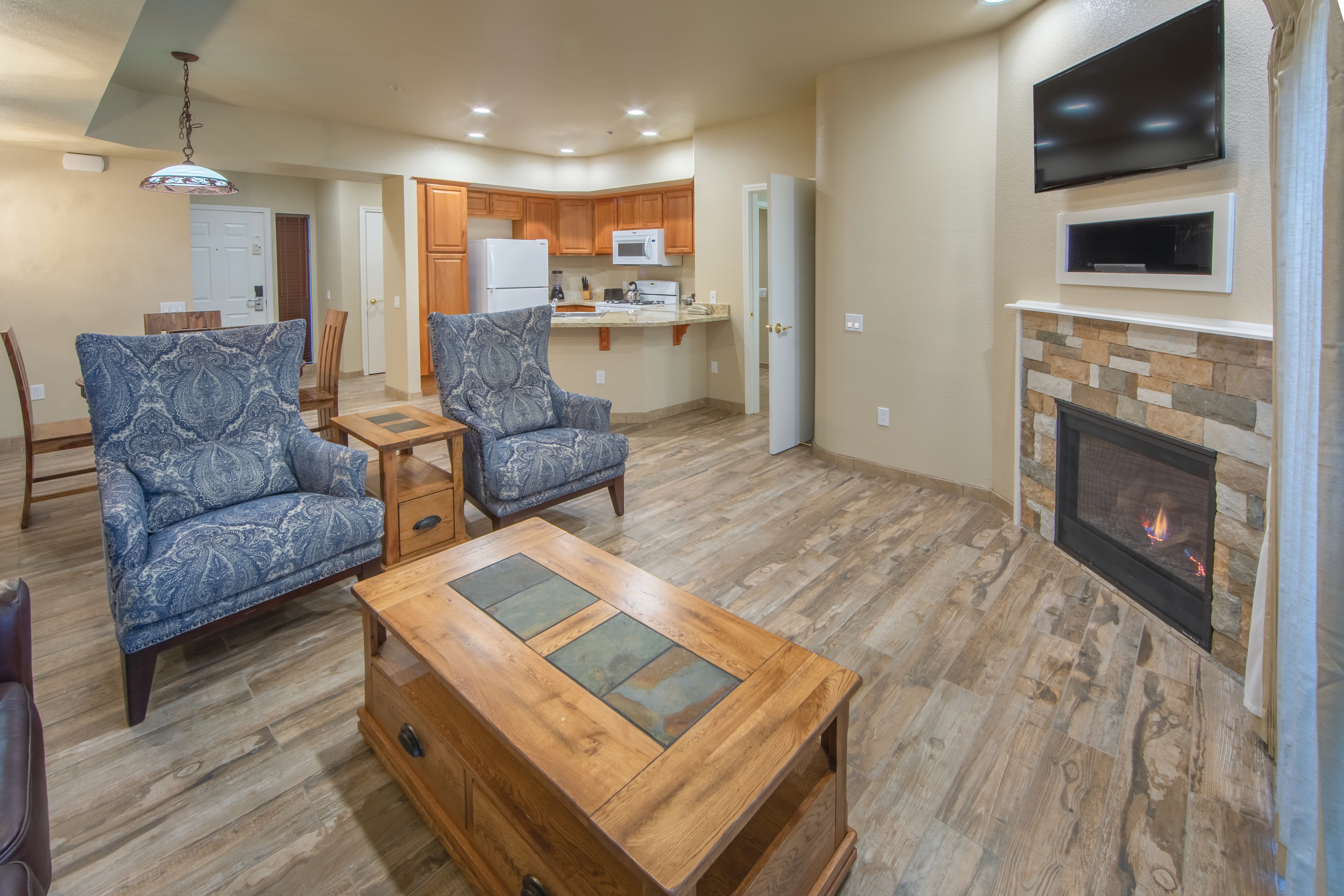 Living room area with fireplace and view of full kitchen in an upgraded one-bedroom villa at David Walley's Resort in Genoa, Nevada