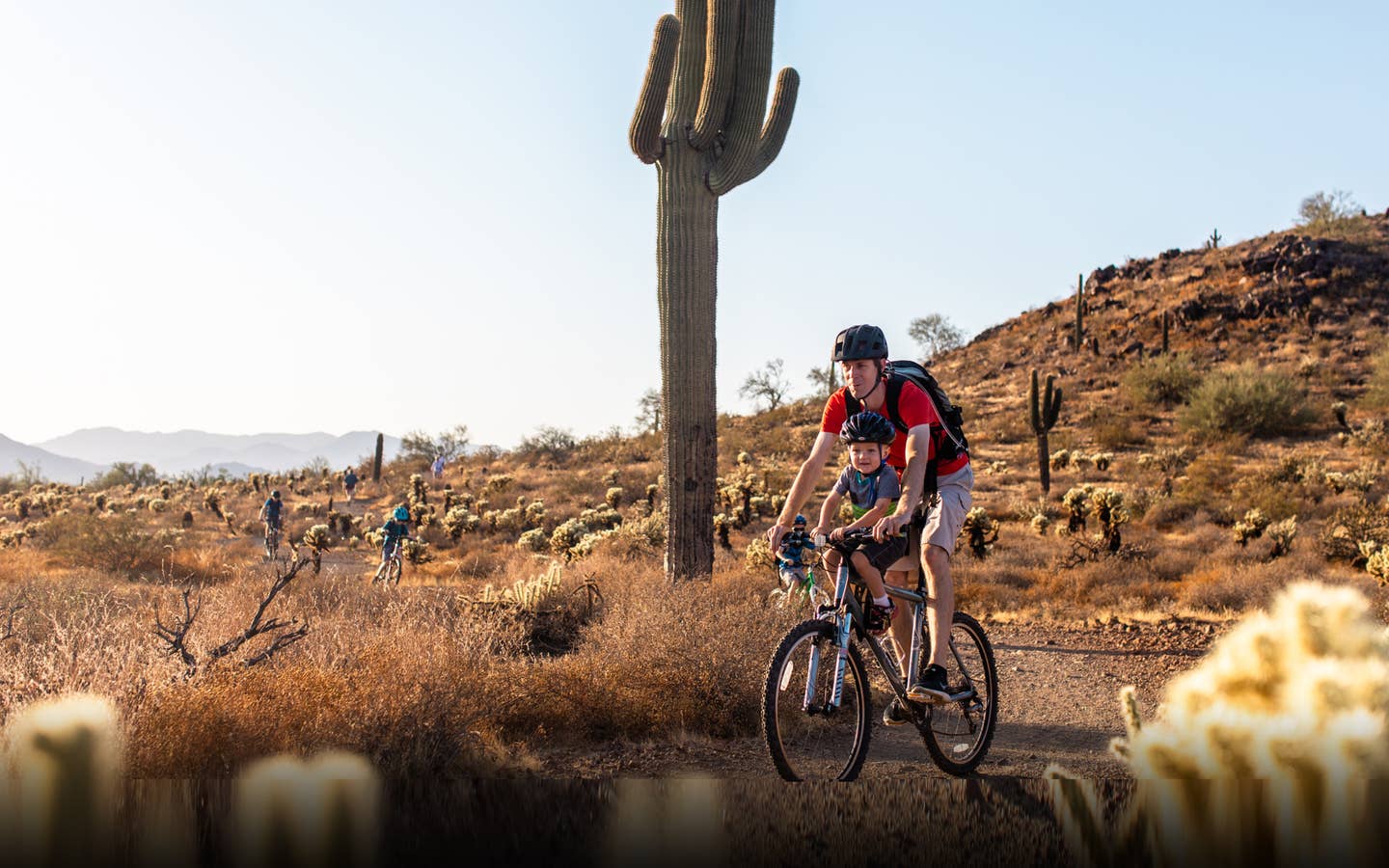 Adult and child riding bike through desert near Scottsdale Resort.