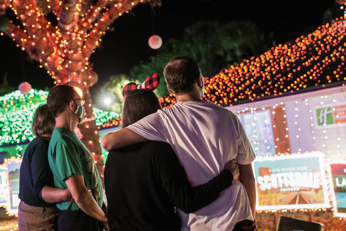 Kyle Bergen (right) and family wear their masks as they look at the exterior Villa decorations with colored string lights and giant postcard designs.
