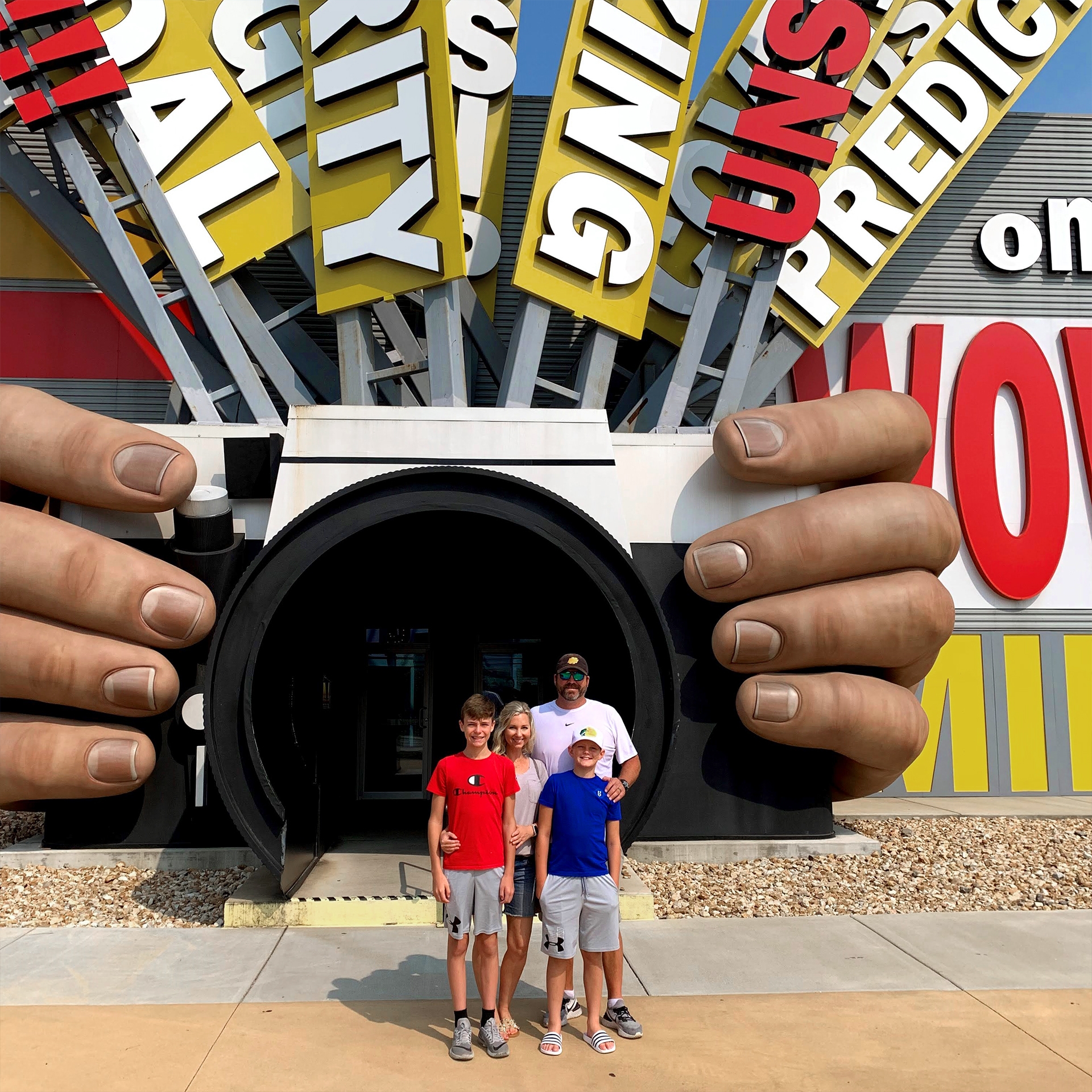 A woman, a man and two boys stand outside a building entrance shaped like a camera.