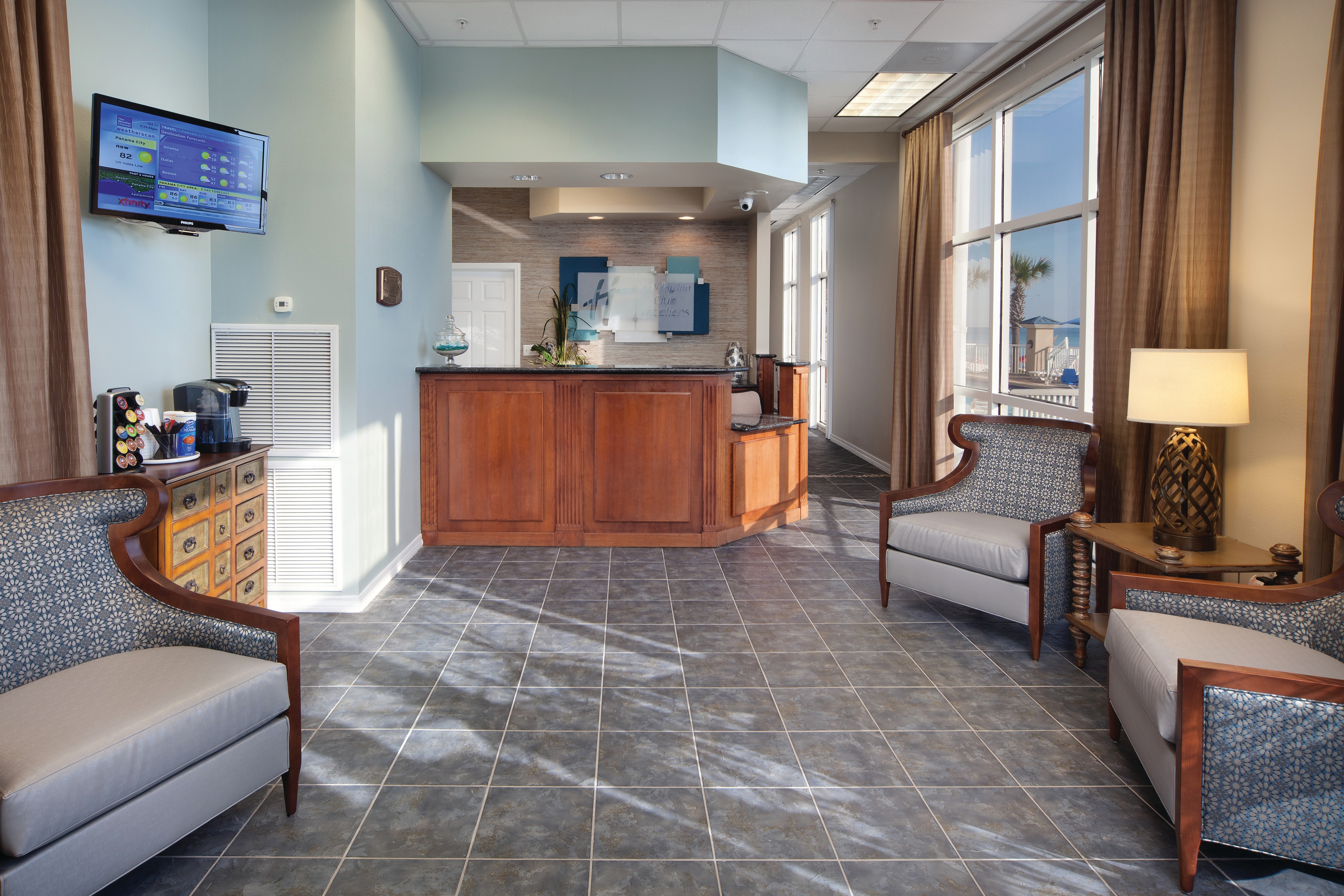 Lobby with reception desk, comfortable seating, and a flat screen TV at Panama City Beach Resort.