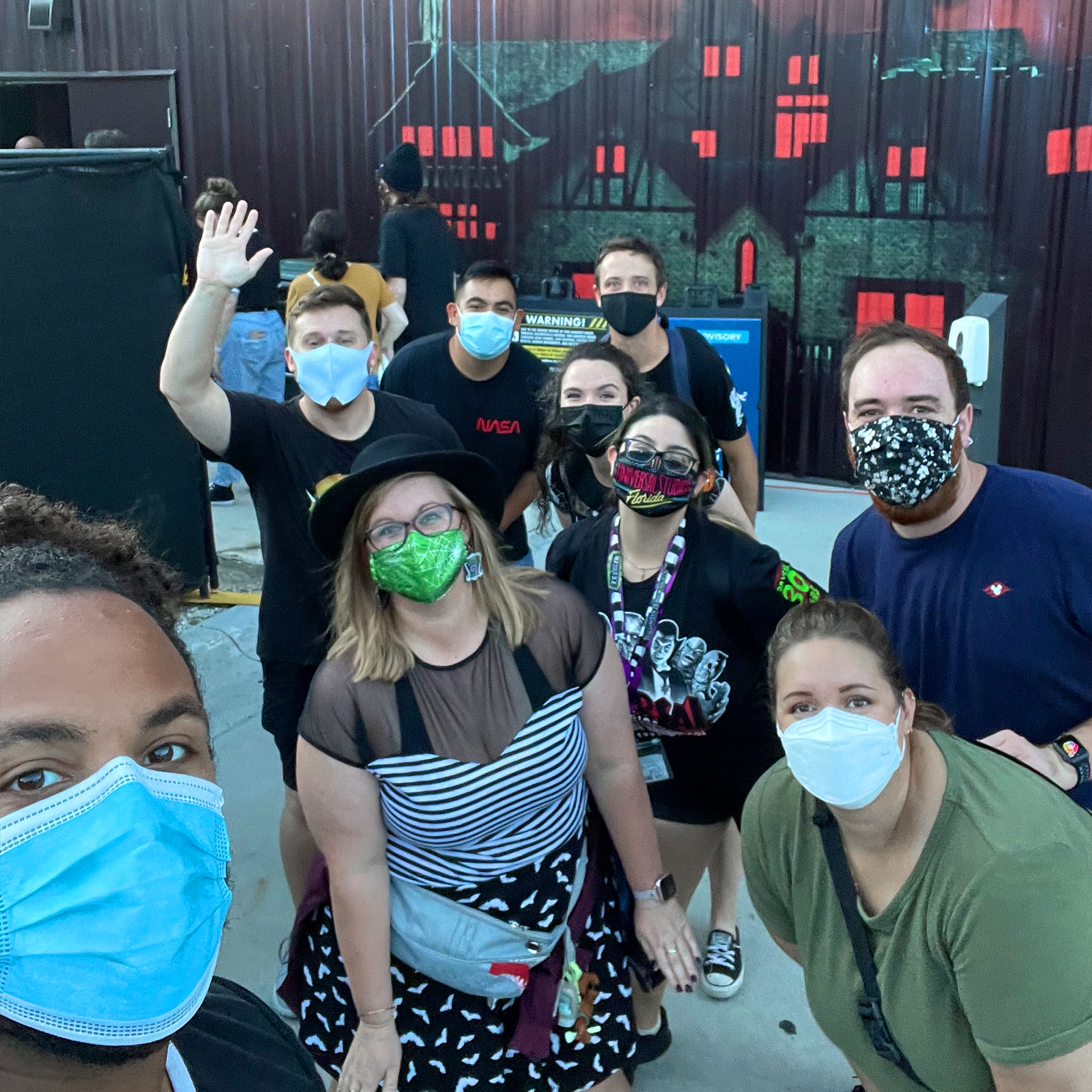A group of men and women wear safety masks outside of a haunted house.
