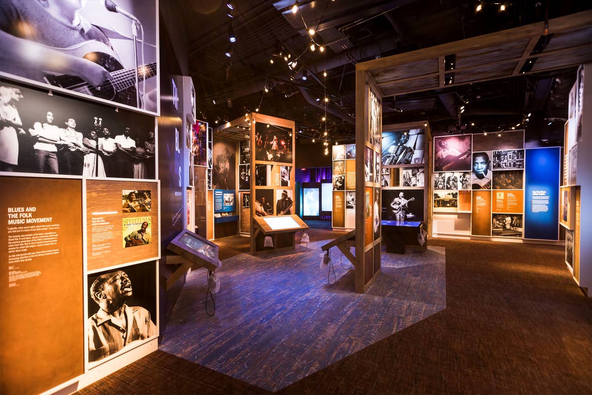 A museum with several interactive stations displays famous African American musicians from decades on wall displays.