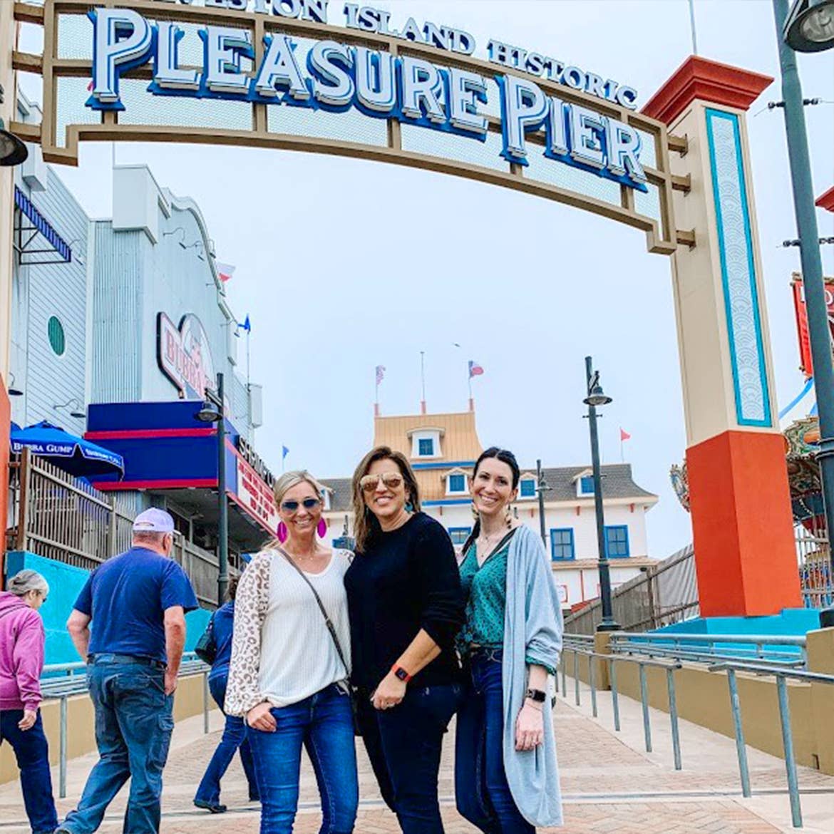 Featured Contributor, Amanda Nall (left) poses with her two friends in front of the Paradise Pier in Galveston, Tx.
