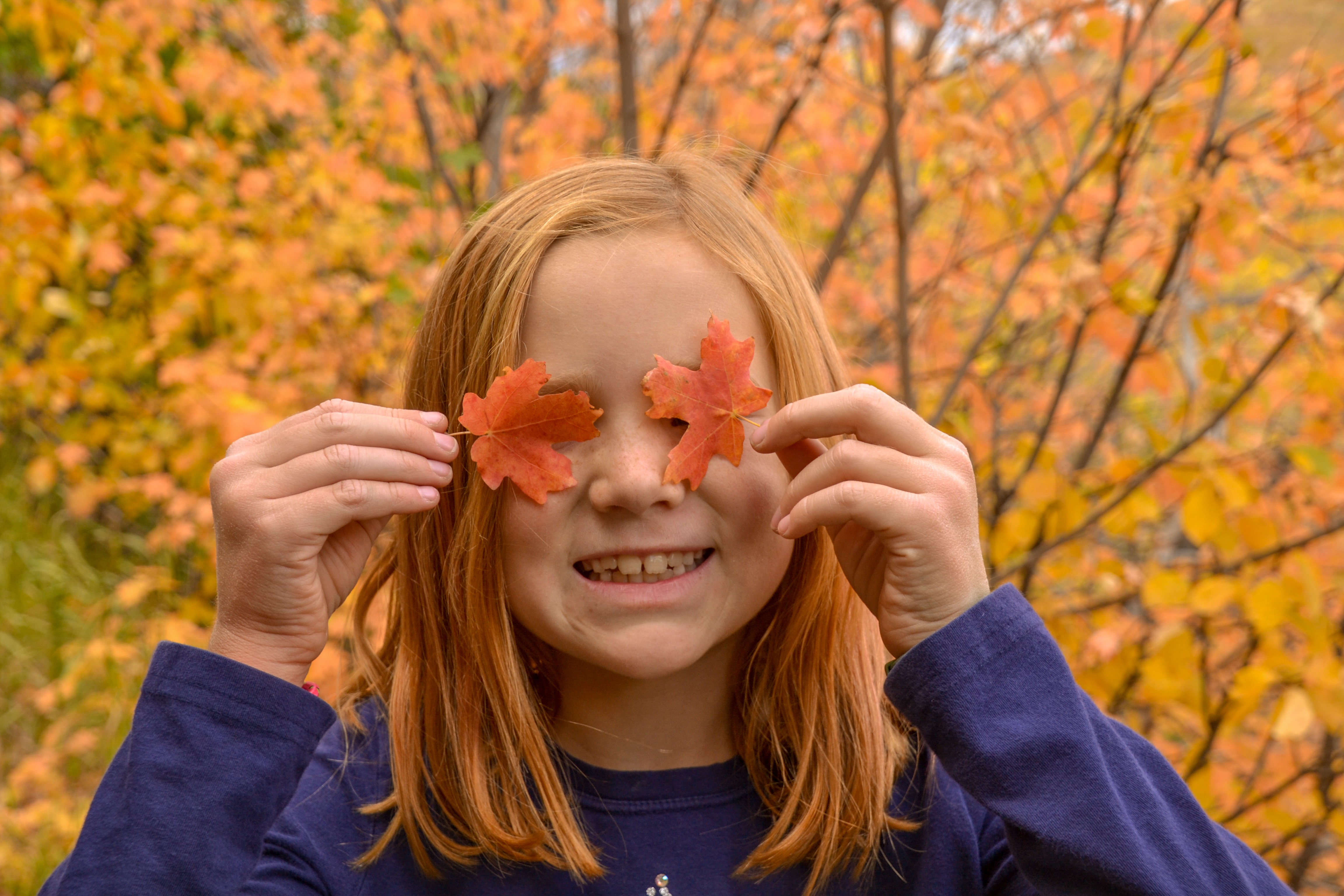 Jessica's daughter covering her eyes with small orange leaves