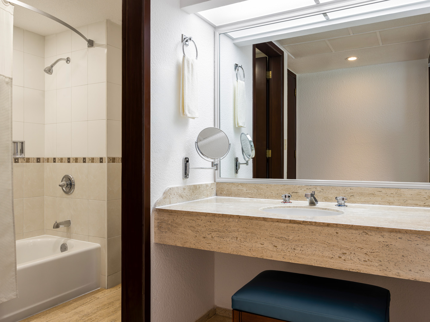 Spacious bathroom with tub, large mirror, and stone counter.