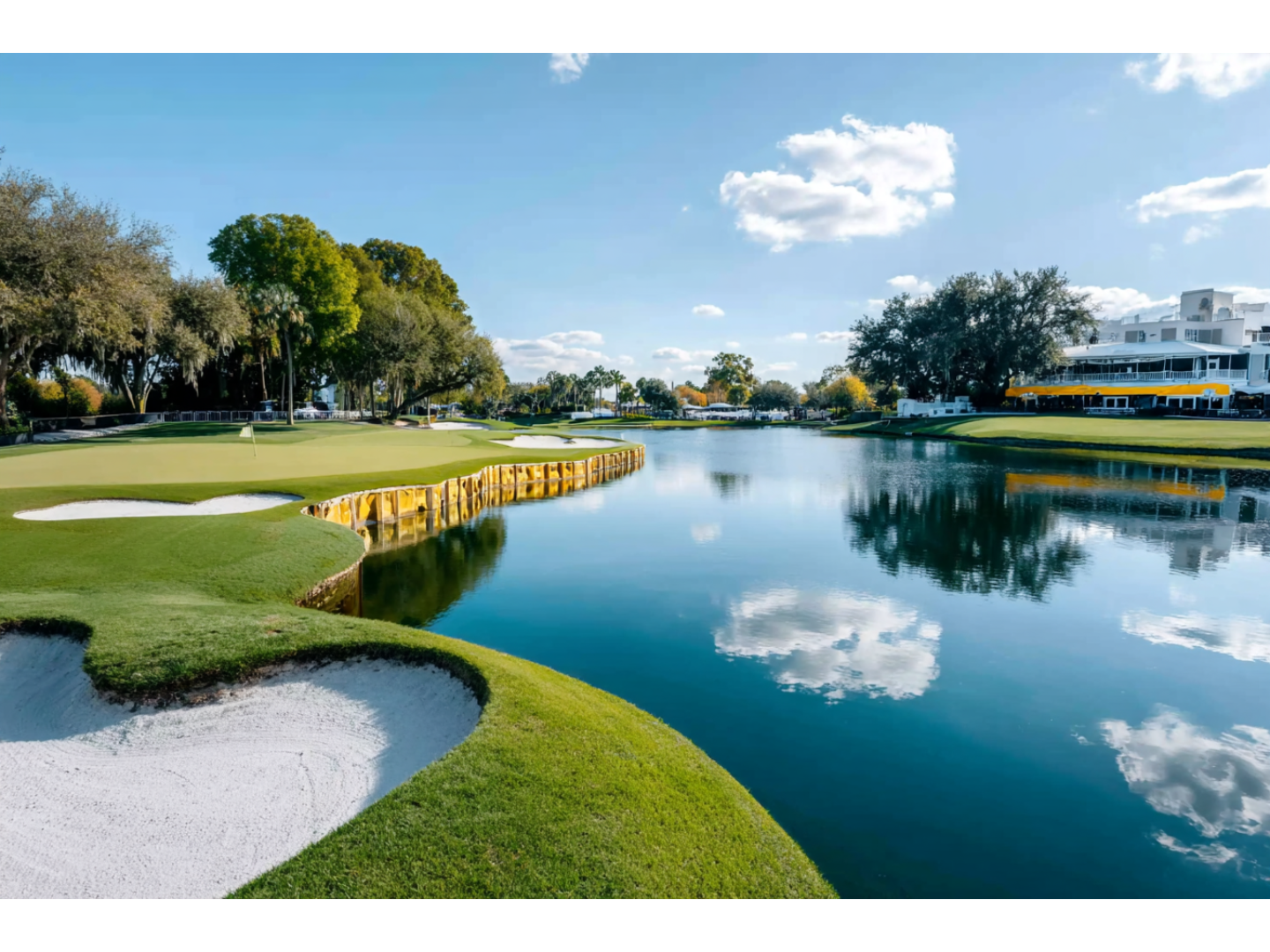 Beautiful golf course with reflective water feature and blue sky.