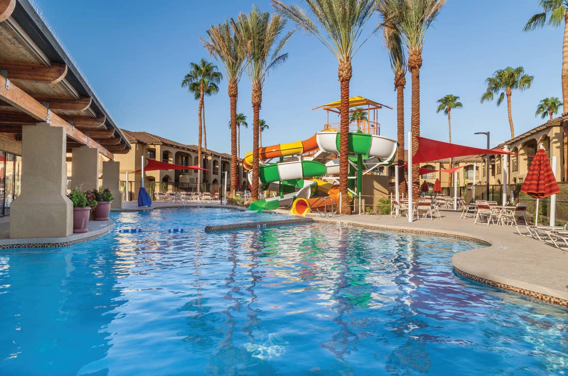 Swimming pool with tables and chairs and a large water slide at Scottsdale Resort in Arizona