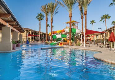 Swimming pool with tables and chairs and a large water slide at Scottsdale Resort in Arizona.