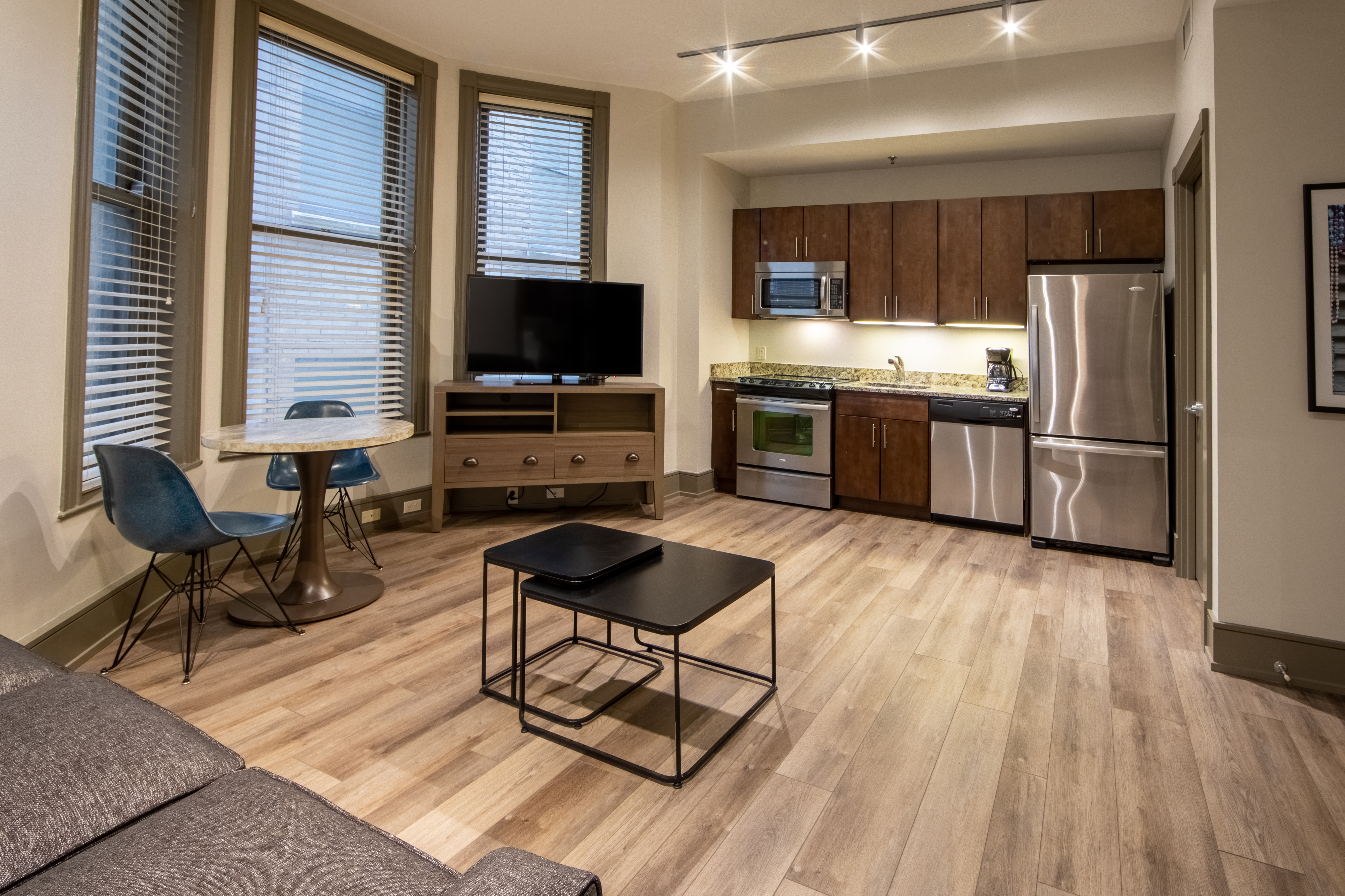 One bedroom villa living area with couch, three windows, TV and full kitchen at New Orleans Resort in Louisiana.