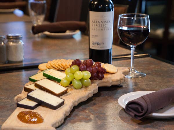 Cheese plate with cheeses, grapes and red wine.