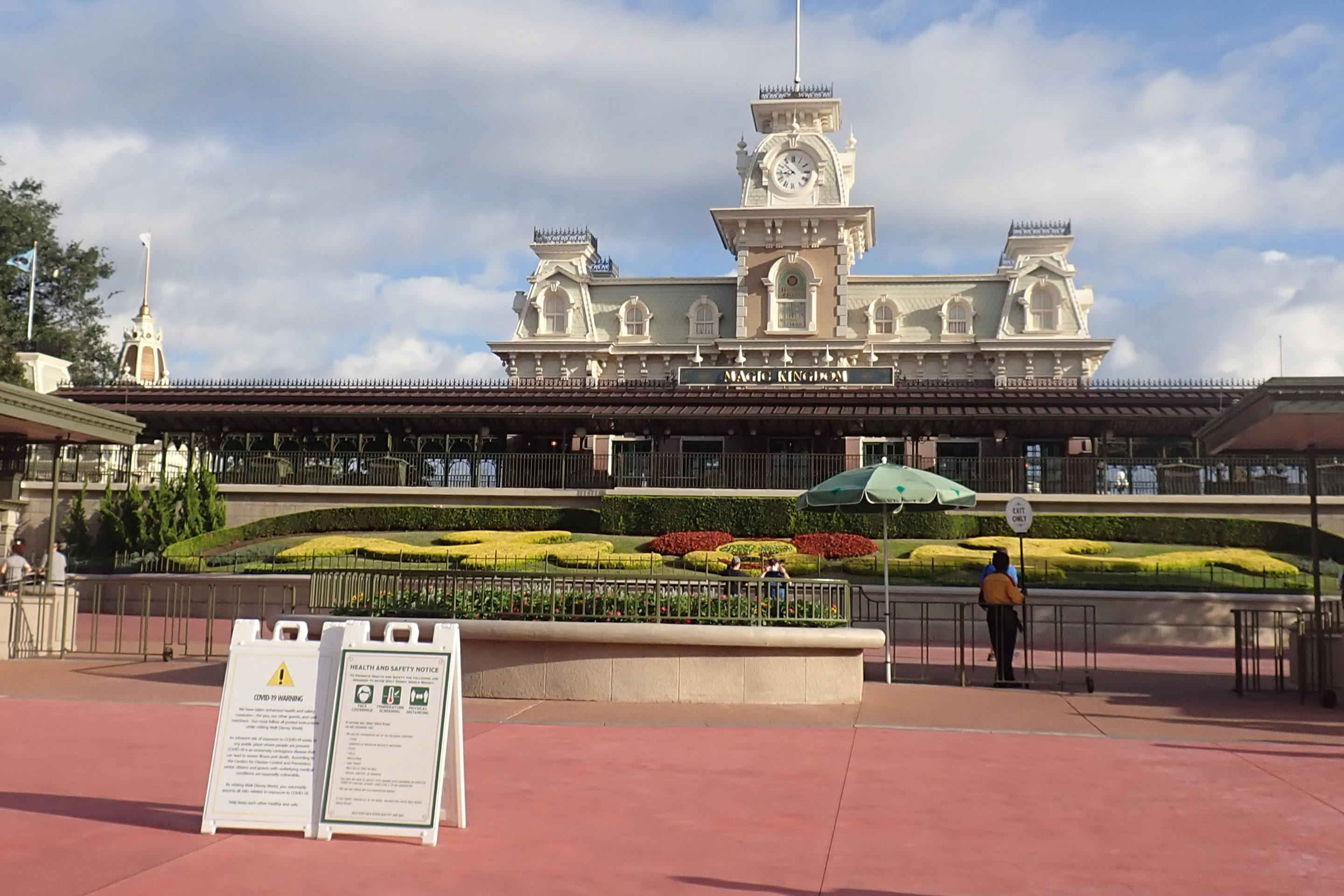 The Magic Kingdom Esplanade with the Walt Disney World Railroad Station and COVID-19 Safety Rule signage posted.