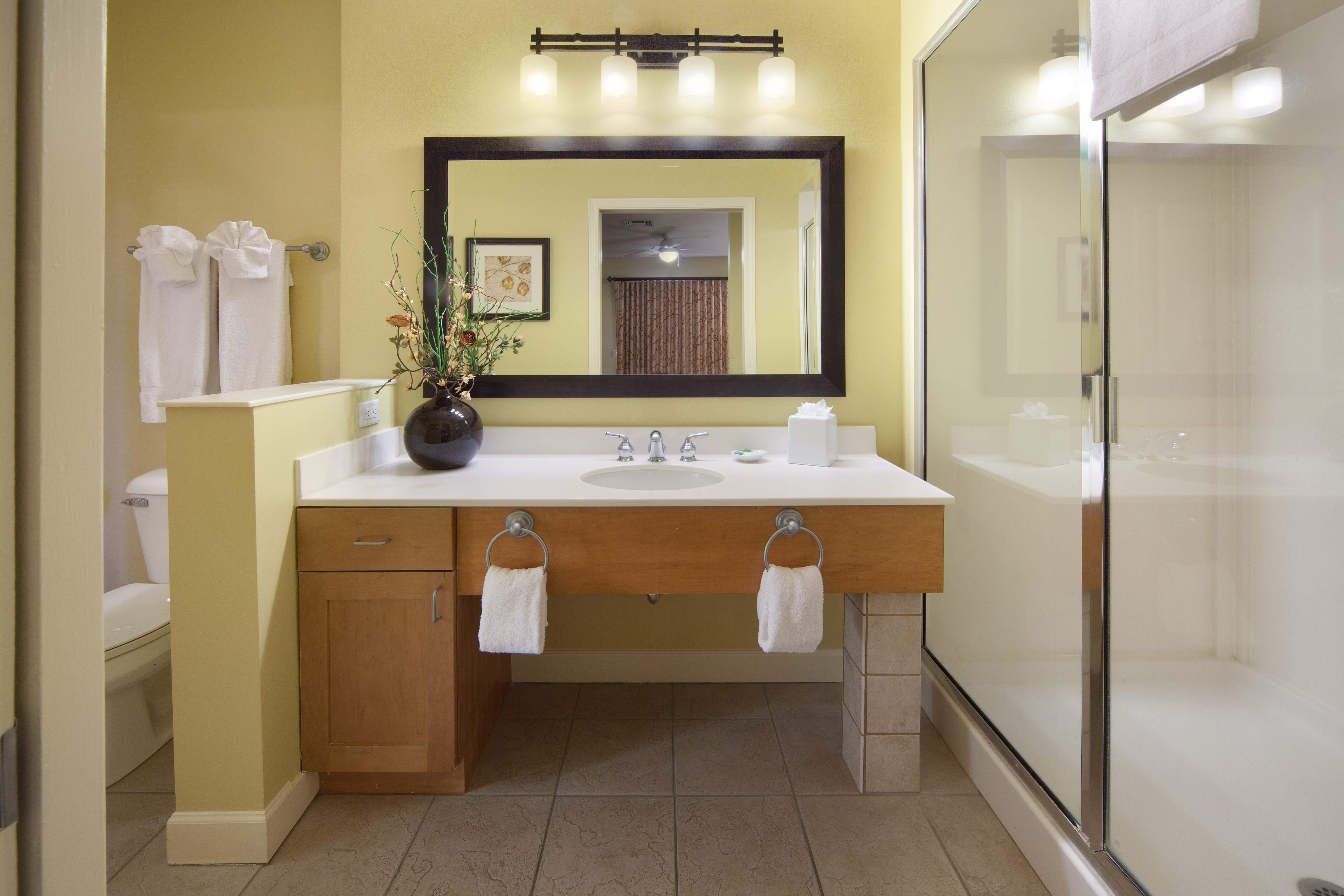 Bathroom with walk-in shower, sink with large mirror, and toilet in a one-bedroom villa at Lake Geneva Resort