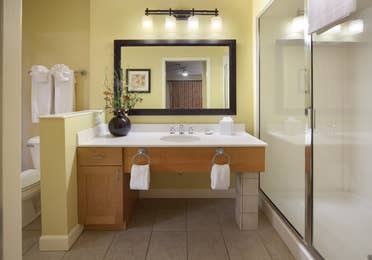 Bathroom with walk-in shower, sink with large mirror, and toilet in a one-bedroom villa at Lake Geneva Resort