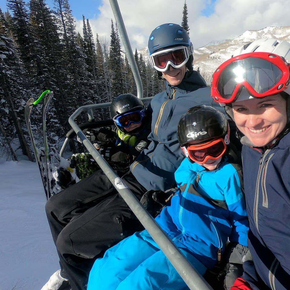 Author, Jessica Averett, and her family sit on the ski lift in winter apparel and ski gear.