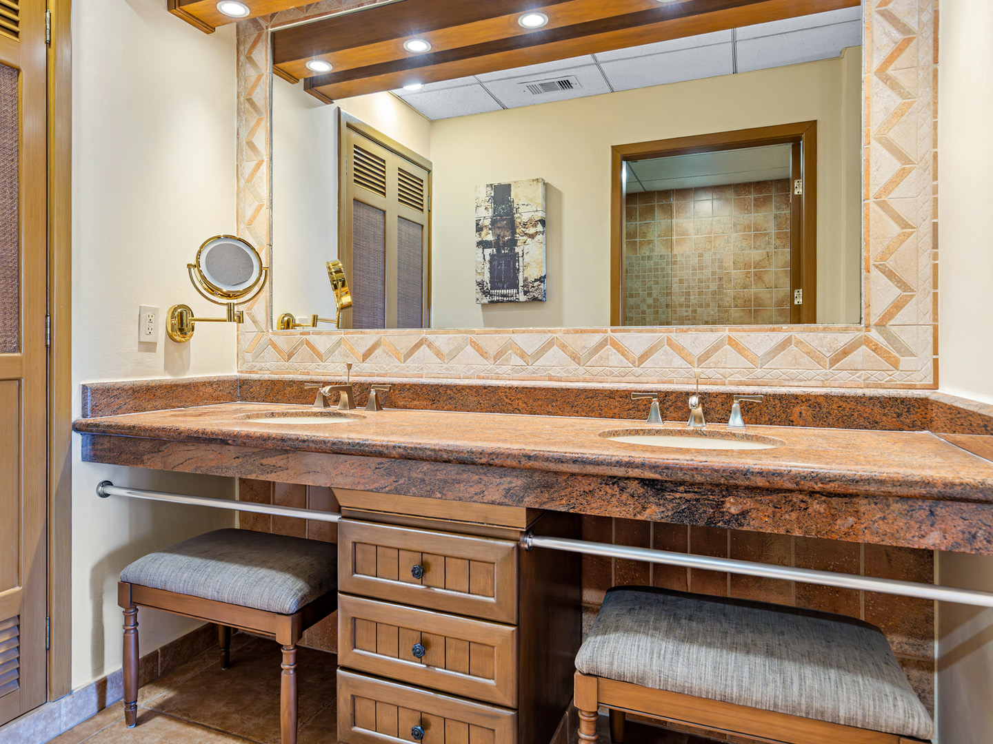 Elegant bathroom with double sinks, seating, and large mirror.