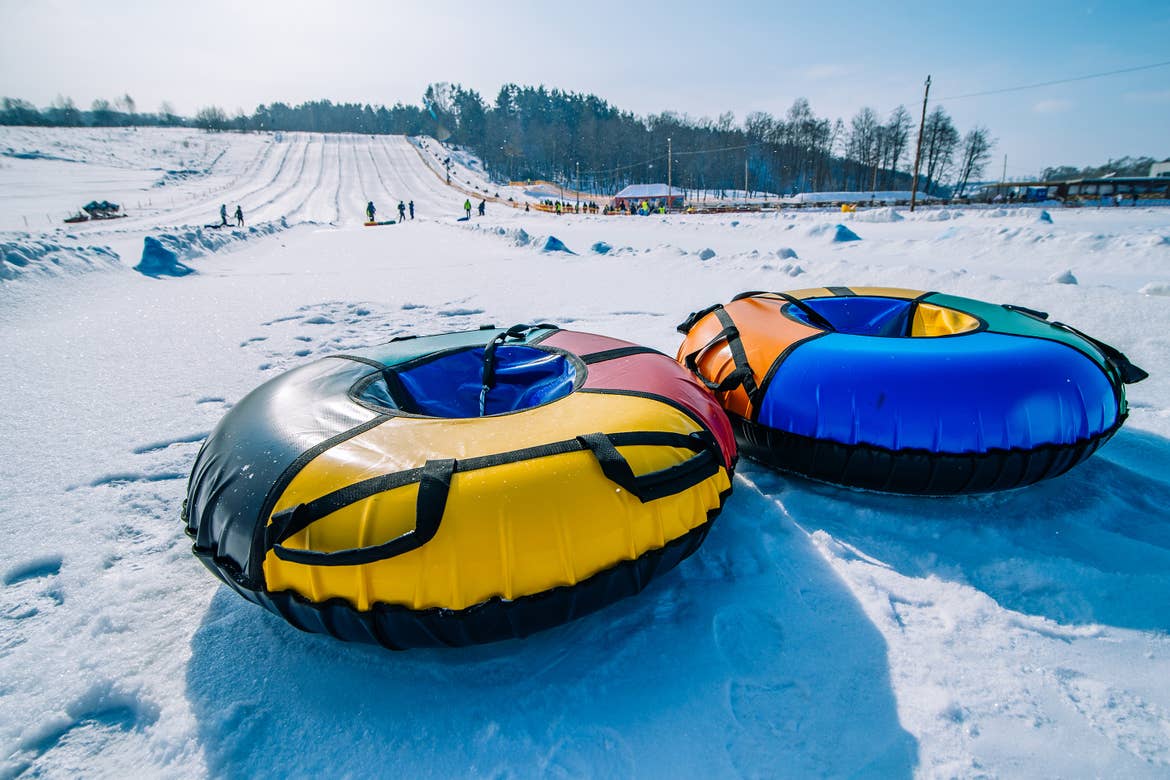 Two inflatable inner tubes at the bottom of a snowy incline.