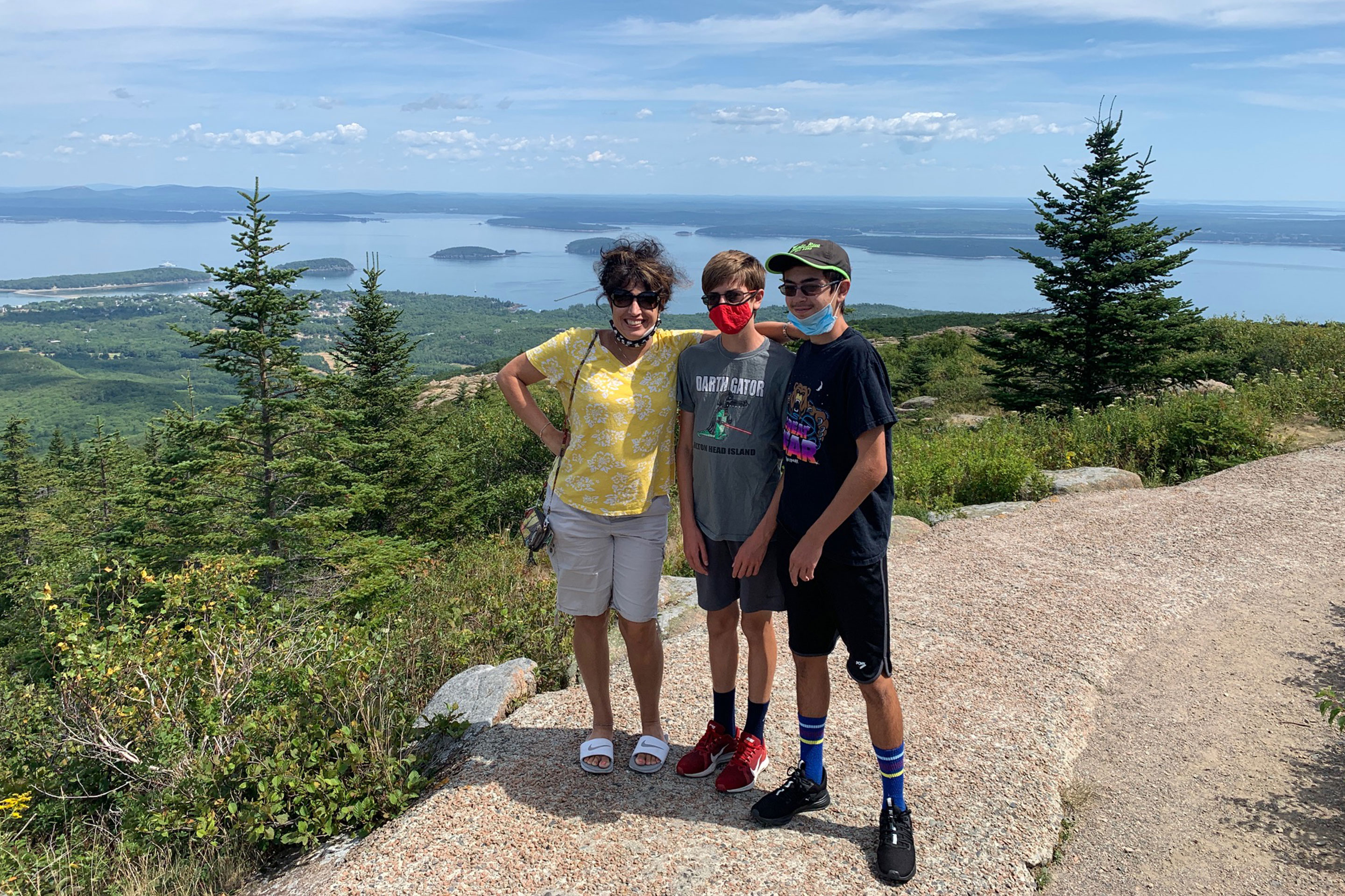 Author, Jennifer Probst (left), and her sons (middle and right) stand on the edge of the Acadia National Park hiking trail while wearing their masks.