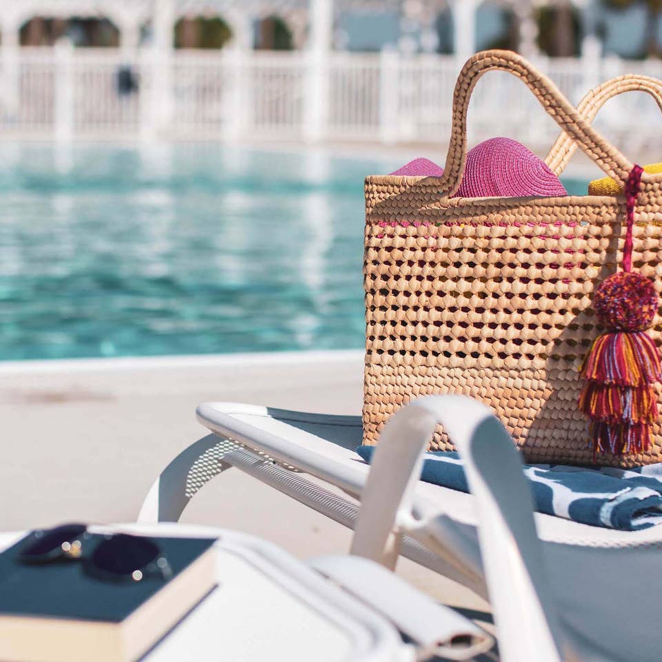 Pool bag, book and sunglasses sitting on pool chair by outdoor pool at Orlando Breeze Resort in Florida.