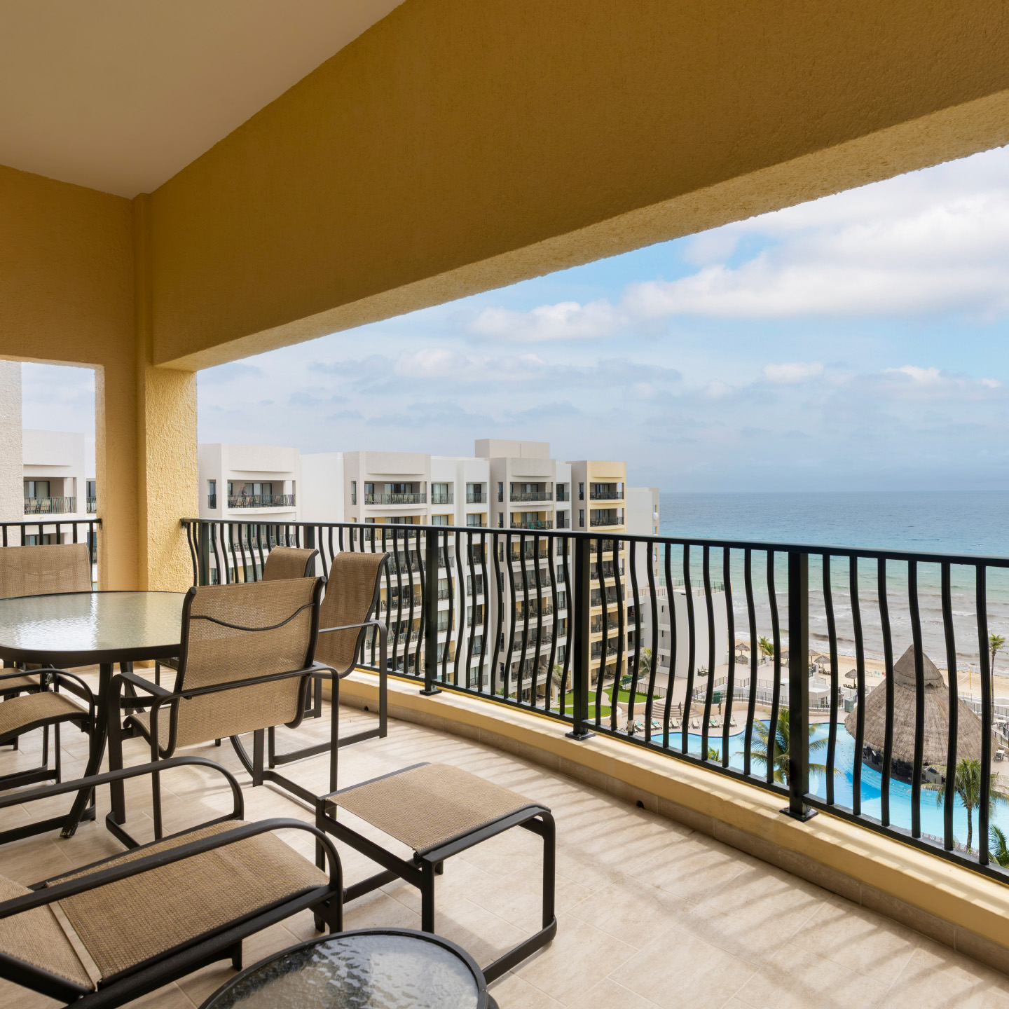 Spacious resort-view balcony with loungers and dining set. 