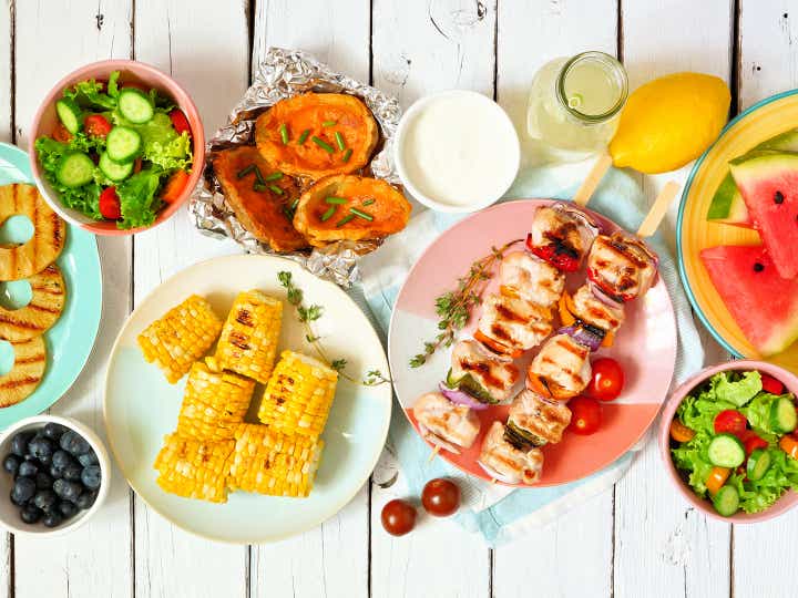 An array of grilled food on a picnic table