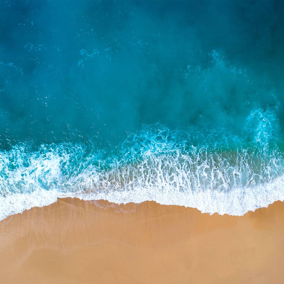 Aerial view of ocean wave crashing onto the shore.