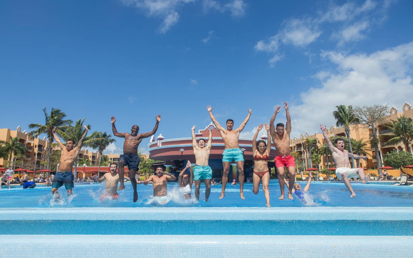 Group of friends jumping into pool at The Royal Haciendas.
